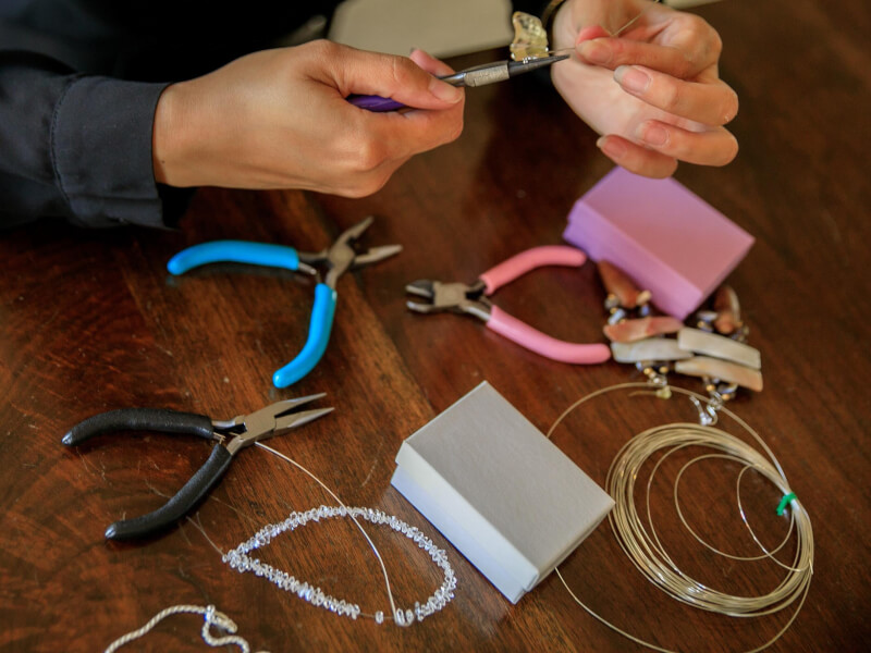 A person using pliers on metal wire for jewellery making.